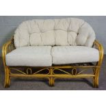 A modern Wicker colonial style settee, with cushioned back, 120cm long