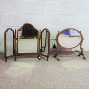 Two dressing mirrors, with with an oval plate, within curved uprights; the other with triple folding