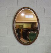 An Edwardian oval mirror on stand, with curved supports, 73cm high, 82cm wide; and another oval