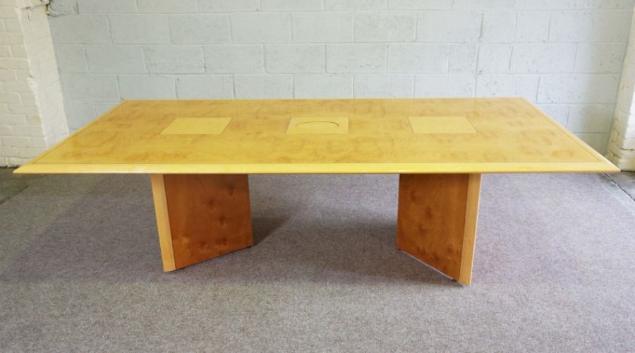 A modern burr veneered boardroom table, with a rectangular top, utility port and set on angled