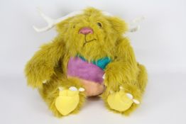 A yellow-coloured soft toy monster with white antlers and glass eyes.