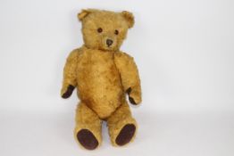 A large unmarked vintage jointed teddy bear. The golden mohair bear stands approx.