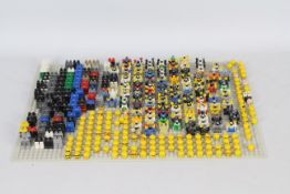 Lego - A collection of more than 50 Lego figures in component form on a Lego base mat.