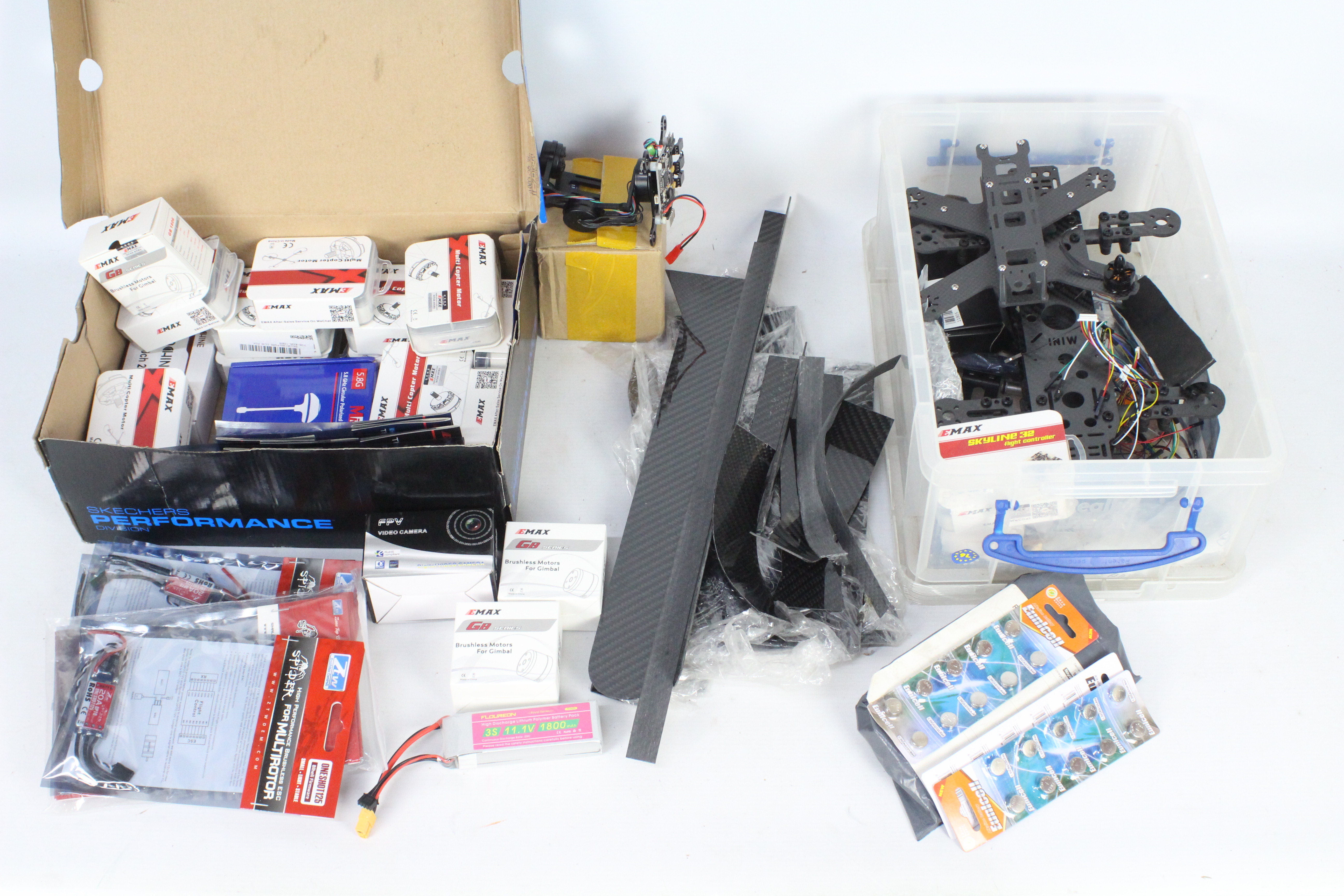 A collection of R/C spare parts and a carbon fibre quad copter frame with a box of brushless motors.