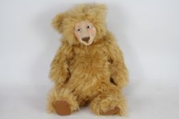 A large mohair bear with glass eyes, suede paws, and wool face. Bear has metal joints.