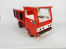 A vintage hand-made wooden tipper truck painted red with black panels and white driver's cab,