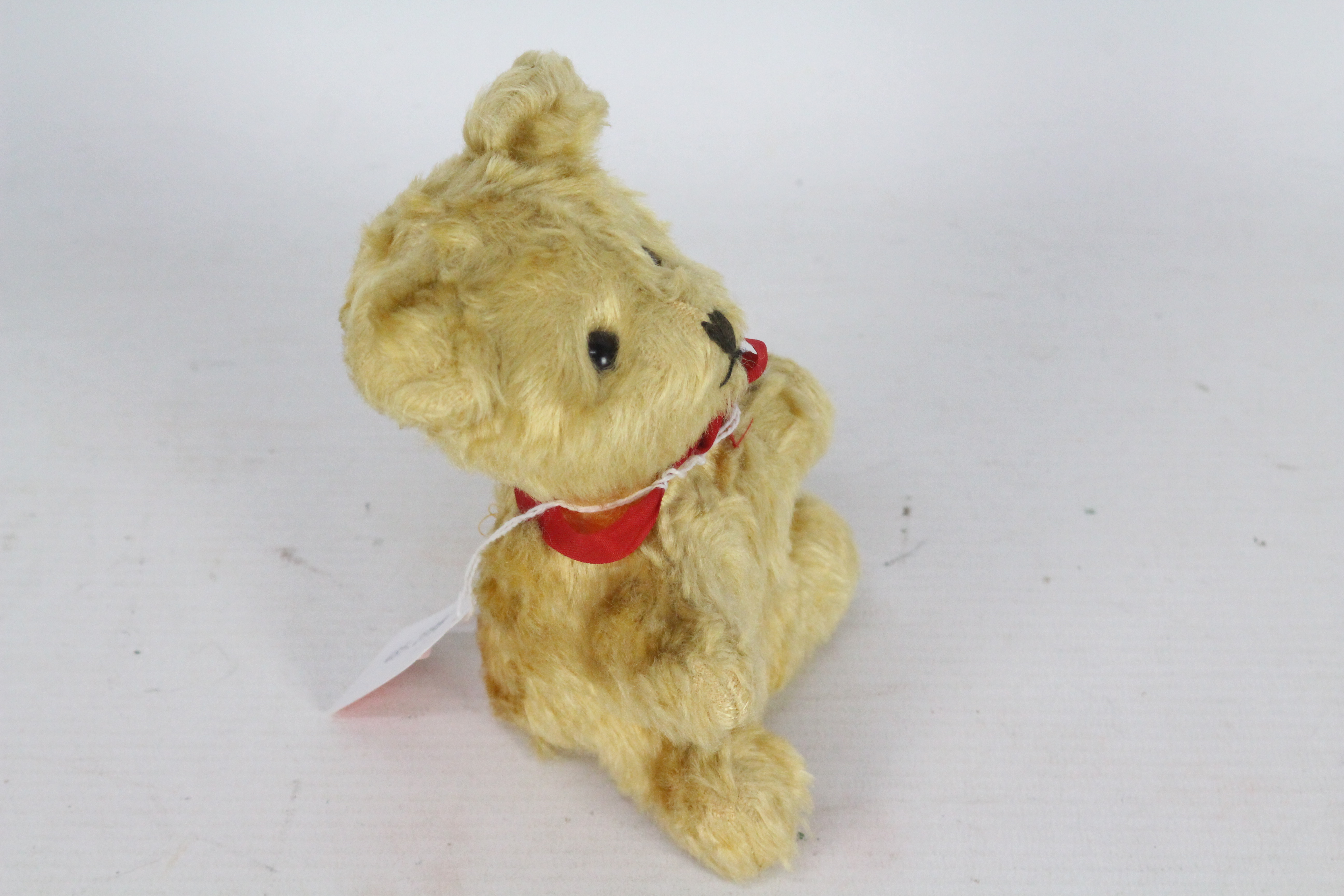 A mohair teddy bear with glass eyes. Bear has a red bow-tie. Bear is 14 cm in height. - Image 3 of 4