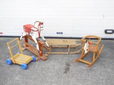 A collection of 2 wooden rocking horses, a sled and a trolley. All wooden and playworn as pictured.
