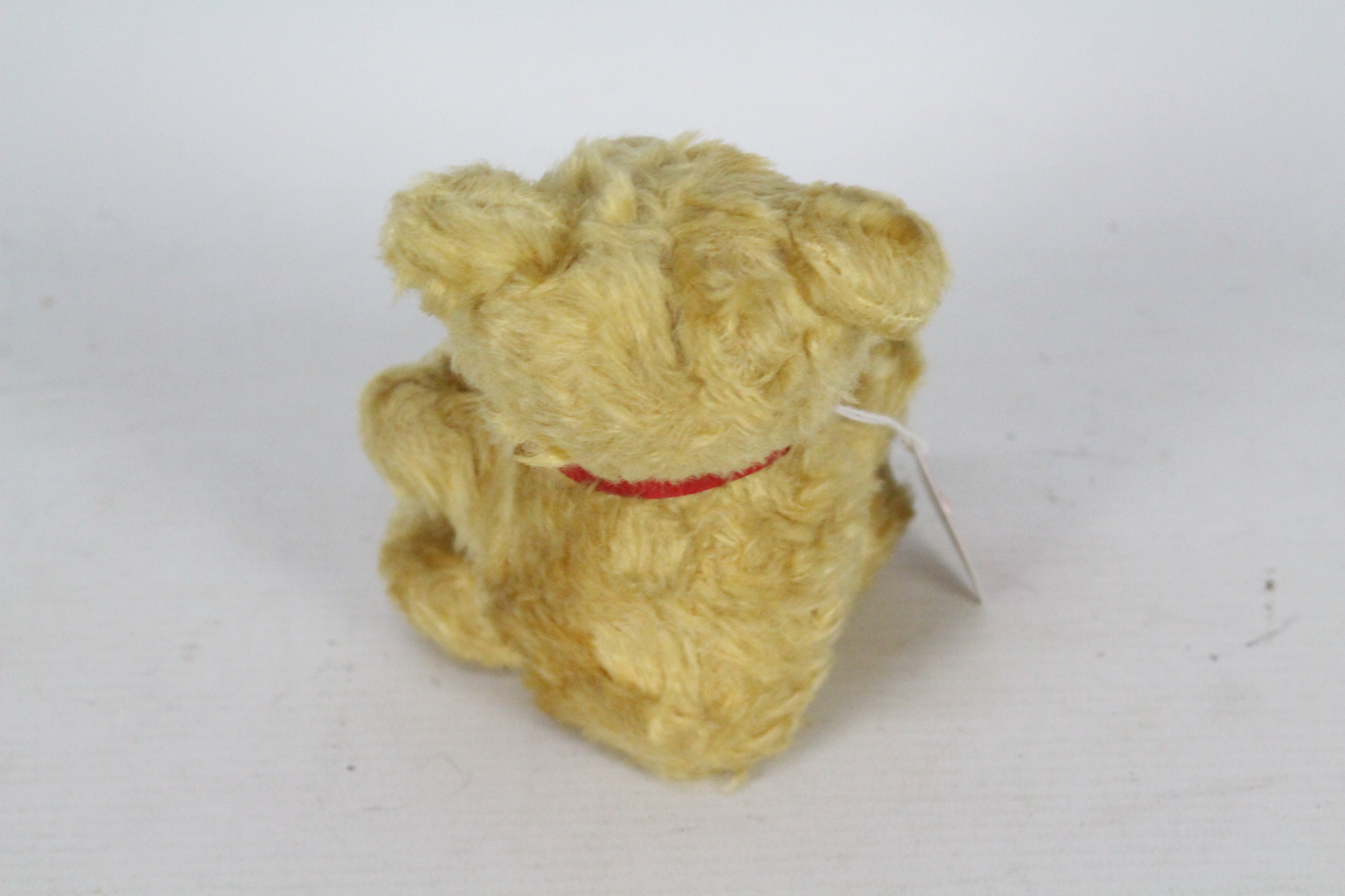 A mohair teddy bear with glass eyes. Bear has a red bow-tie. Bear is 14 cm in height. - Image 4 of 4
