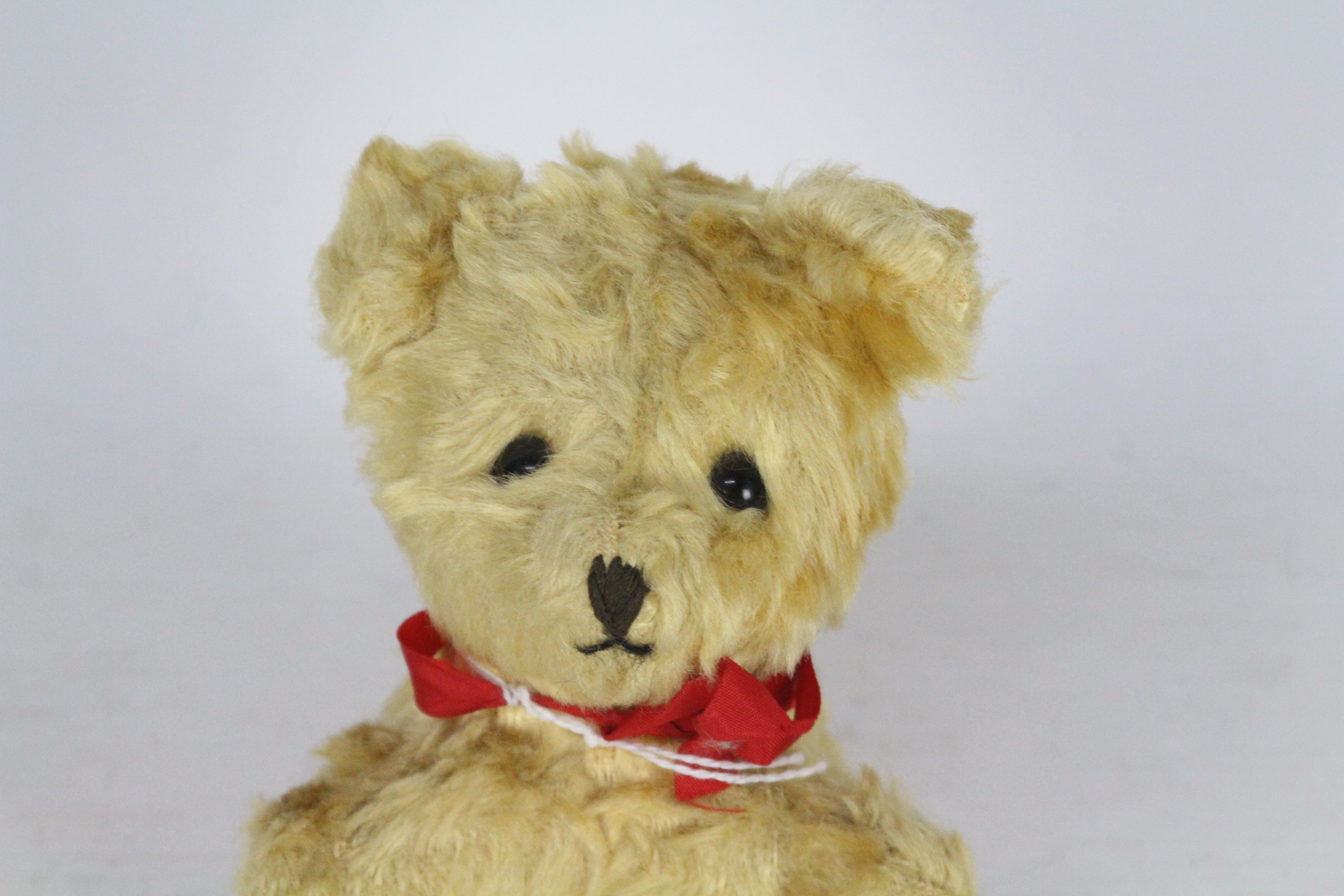A mohair teddy bear with glass eyes. Bear has a red bow-tie. Bear is 14 cm in height. - Image 2 of 4
