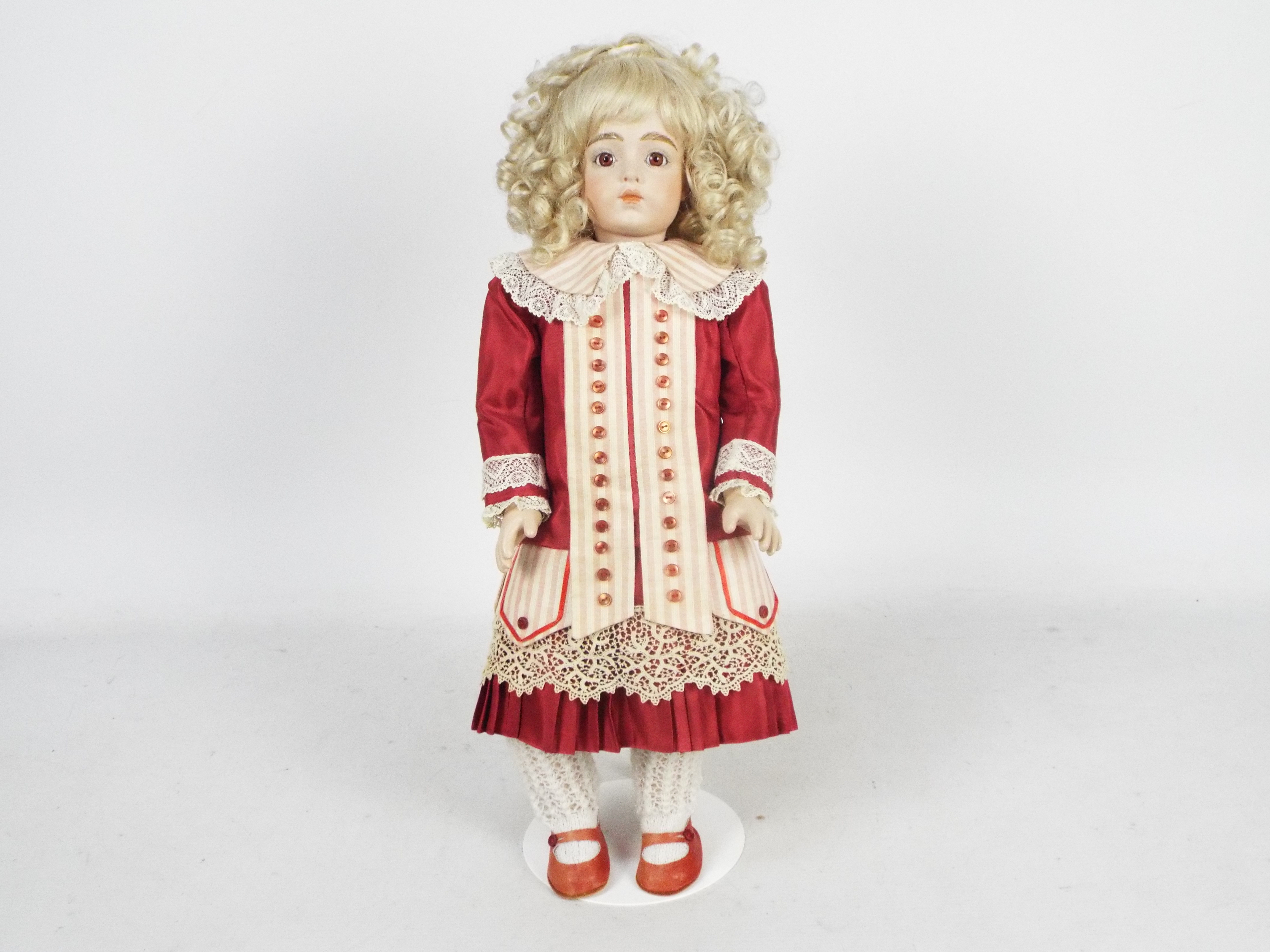 Bru Jne - A reproduction of a Bru Jne bisque head doll on stand.