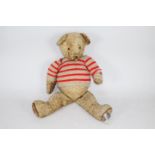 A large unmarked jointed vintage teddy bear. The golden wool type plush bear stands approx.