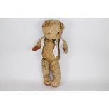 A large unmarked vintage teddy bear with jointed arms and legs. The golden bear stands approx.