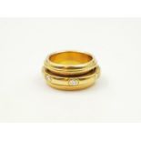 A PIAGET 18K GOLD RING WITH ROTATING CENTRE BAR CONTAINING BRILLIANT DIAMONDS. 11.5gms size H