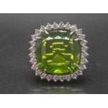 An 18 K white gold ring with a large cushion cut peridot (probably Burmese in origin) surrounded
