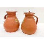 A pair of terracotta coloured Cambridge Ale jugs made by Wedgewood, each with a different coat of