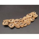 An Early Chinese Bone - Multiple Skull Pendant. 9.5cm.