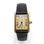 A CARTIER TANK WATCH IN GOLD PLATED SILVER WITH ROMAN NUMERALS AND ORIGINAL CARTIER LEATHER STRAP.