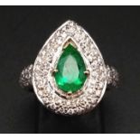 AN 18K WHITE GOLD DIAMOND ENCRUSTED TEAR DROP SHAPED RING WITH MATCHING SHAPED EMERALD CENTRE STONE.