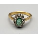 An 18 K yellow gold ring with an oval emerald surrounded by a halo of diamonds. Ring size: M,