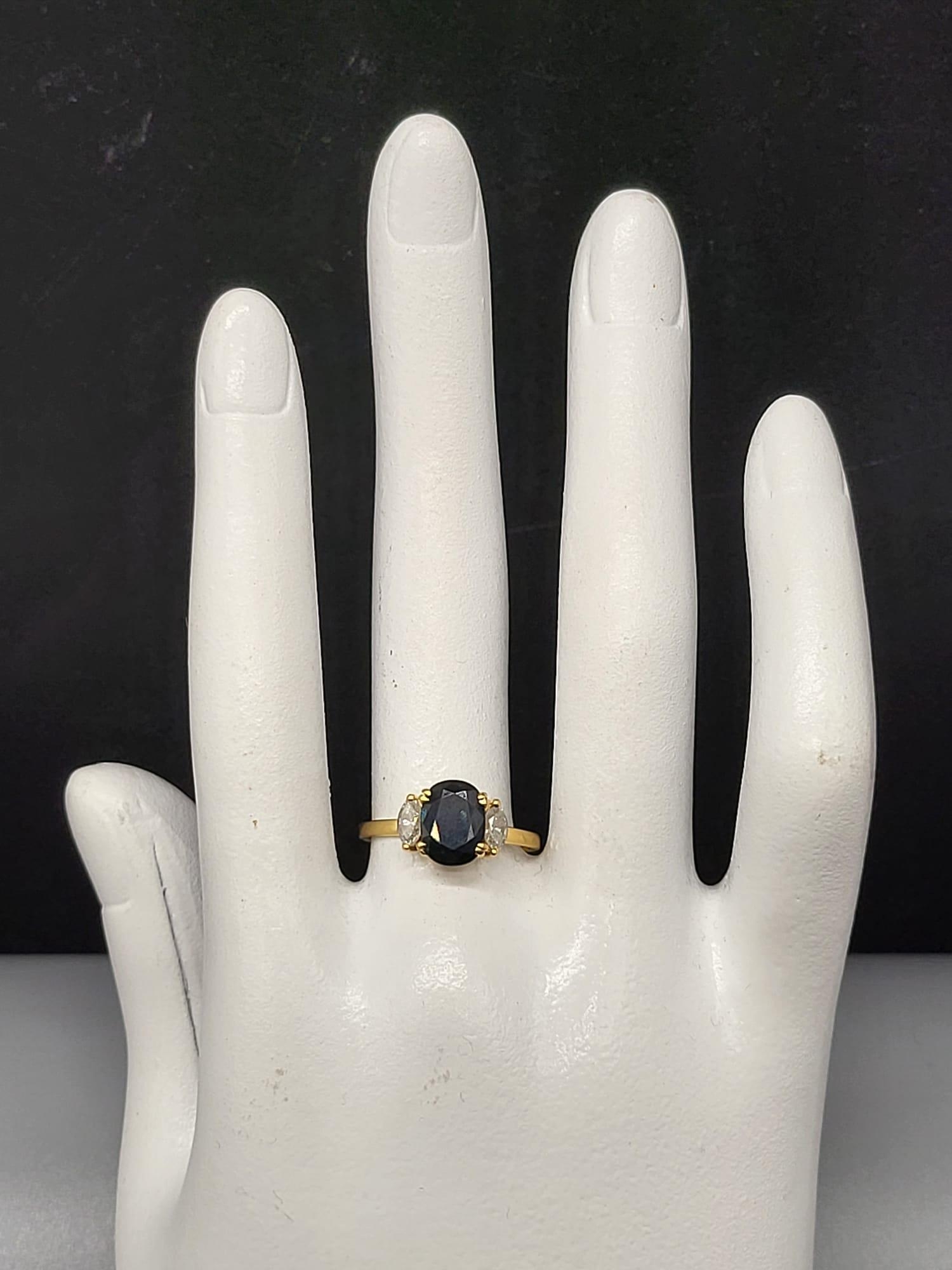 An 18 K yellow gold ring with an oval cut dark blue sapphire, flanked by two marquise cut sapphires. - Image 5 of 5
