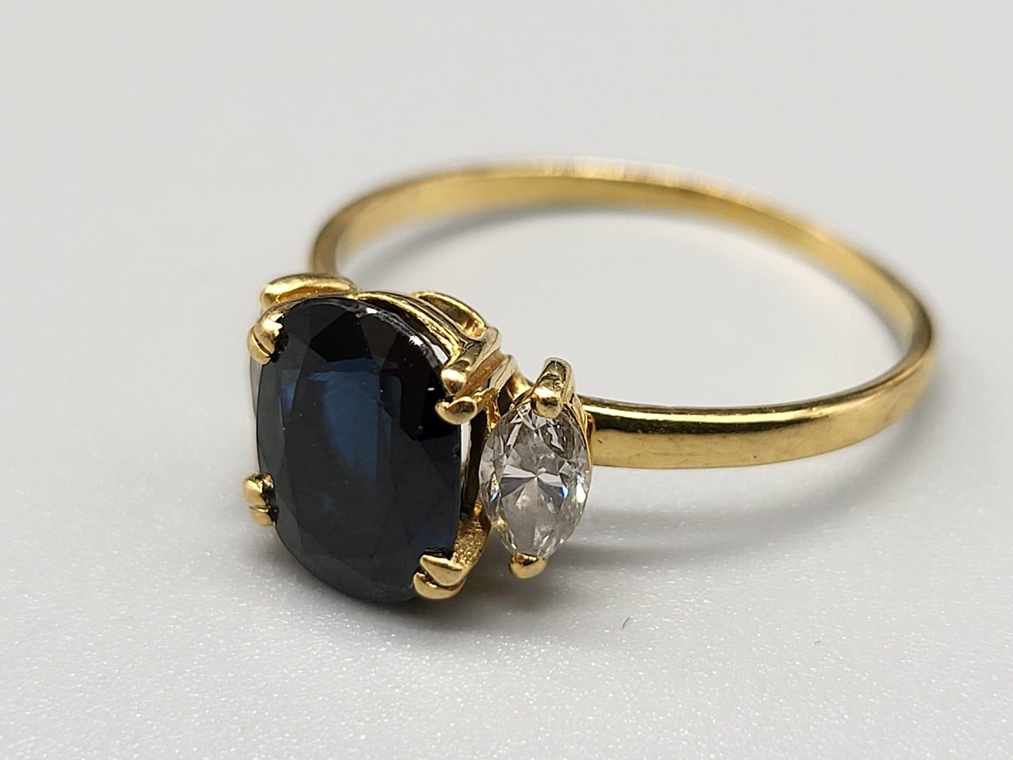 An 18 K yellow gold ring with an oval cut dark blue sapphire, flanked by two marquise cut sapphires. - Image 2 of 5
