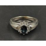 An 18K White Gold Diamond and Sapphire Ring. Centre stone sapphire surrounded by a halo of diamonds.