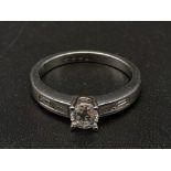 An 18K White Gold Diamond Ring. Central stone with diamond shoulders. 0.60ct. Size M. 4g.