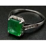 An 18k White Gold (tested) Emerald and Diamond Ring. Emerald centre stone surrounded by small