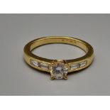 An 18K Yellow Gold Diamond Ring. Central diamond with diamonds on shoulders. 0.60ct. Size M. 4g.
