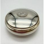 A ROUND SOLID SILVER TRINKET BOX WITH A SILVER OTTOMAN COIN IN THE LID. 57.7gms 8.5cms diameter.