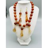 A beautiful, banded, orange agate necklace and earrings set with hand carved lilies. Necklace