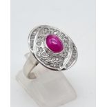 An 18K White Gold Burma Star Ruby and Diamond Ring. Central Burma Star ruby surrounded by a