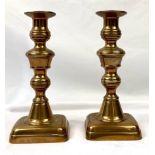 AN ANTIQUE PAIR OF BRASS CANDLESTICKS STANDING 23.5cms IN HEIGHT AND HAVING AN ART DECO DESIGN .