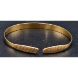 An 18K Yellow Gold Expandable Bangle. Decorated with different gold-toned ends. 9.6g.