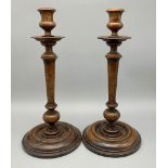 A PAIR OF LARGE WOODEN CANDLESTICKS , SOME AGE RELATED MARKS. A/F 32cms TALL 15cms BASE DIAMETER