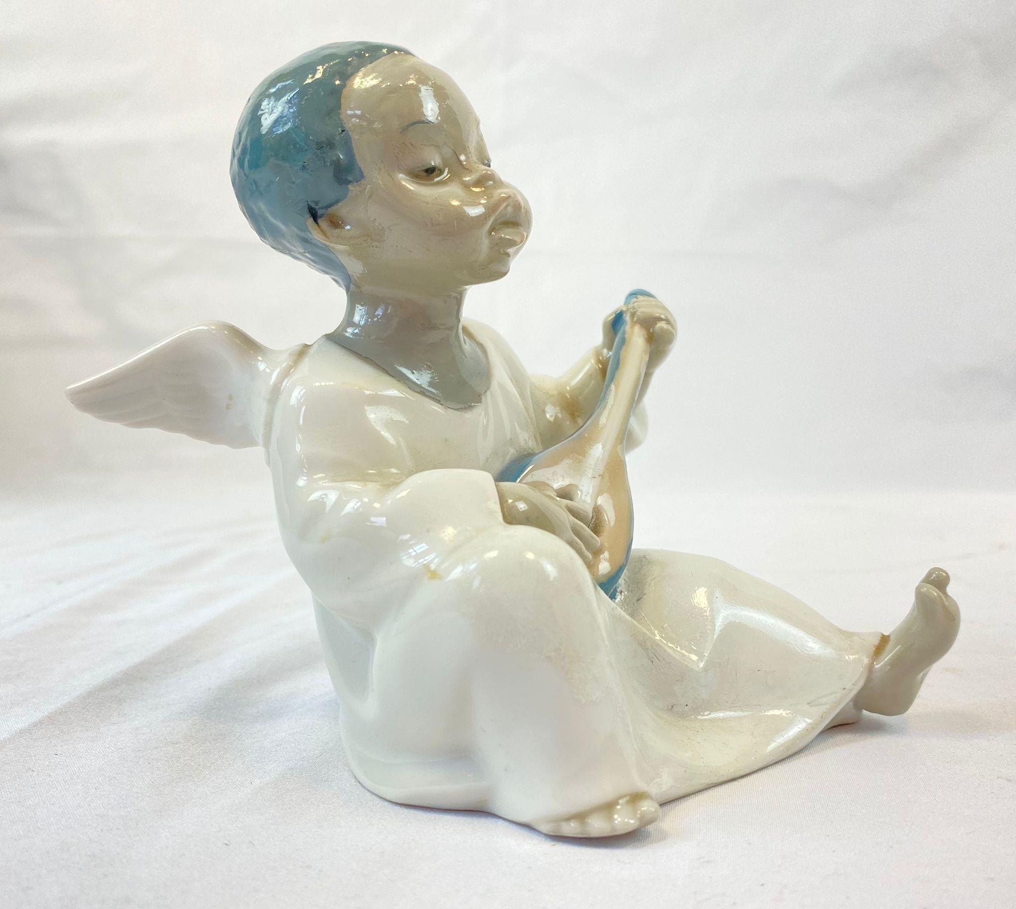 A Lladro figure of a sitting, black boy angel. Hand made in Spain. Height: 11 cm.