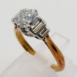 An 18K Yellow Gold Diamond Ring. A .5ct round cut centre stone with two baguette cut diamonds either