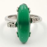 An 18K White Gold (tested) Jade and Diamond Ring. Large oval jade centre stone with two small