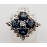 An 18K Yellow Gold Diamond and Sapphire Ring. Four clean blue sapphires surrounded by a cluster of