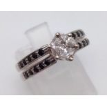 A 9K White Gold Black and White Diamond Ring. Central white diamond with black diamonds on