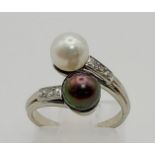 An 18 K white gold ring with two Tahitian pearls (one black, one white) and diamonds on the