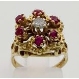 A 9K Yellow Gold Ruby and Diamond Ring. Central diamond surrounded by six rubies. Size J. 3.86g