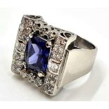 An art deco style platinum ring with diamonds surrounding an attractive blue centre stone. 16.7gms