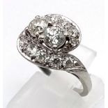 An Antique Platinum and Diamond Ring. Two central round-cut diamonds supported by two waves of