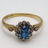 A 9K Yellow Gold Topaz and Diamond Ring. Centre blue topaz surrounded by a halo of diamonds. Size L.