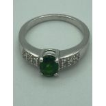 SILVER, GREEN DIOPSIDE RING having oval cut SOLITAIRE mounted to top with white TOPAZ stones pave