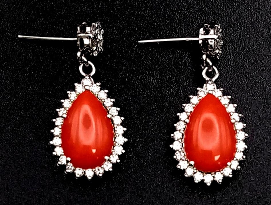 A glamorous pair of 18ct white gold earrings with polished natural red coral and diamonds (1.5