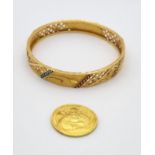 A .999 Gold Ganesha Coin plus a 22K Yellow Gold and Enamel Bangle. Coin - 7.15g. Bangle - 17.69g.