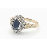 A 9 K yellow gold ring with an oval cut sapphire surrounded by a halo of diamonds. Size: K,